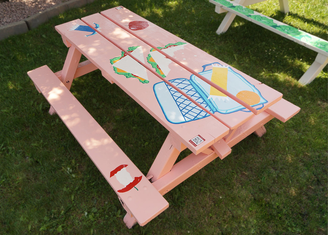 Painted designs on a picnic table of a half eaten sandwich, lunch bag, apples and granola bars